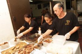 three workers at soup kitchen serving food