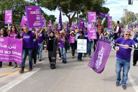 large street march of people holding purple signs and flags with organization's logo