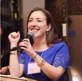 Photo of Rabbi Sara Luria smiling at podum