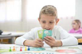 boy holding cards in front of a board game
