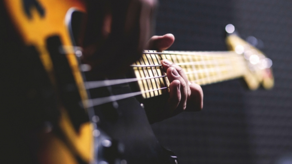 Close-up of a person playing a yellow electric guitar