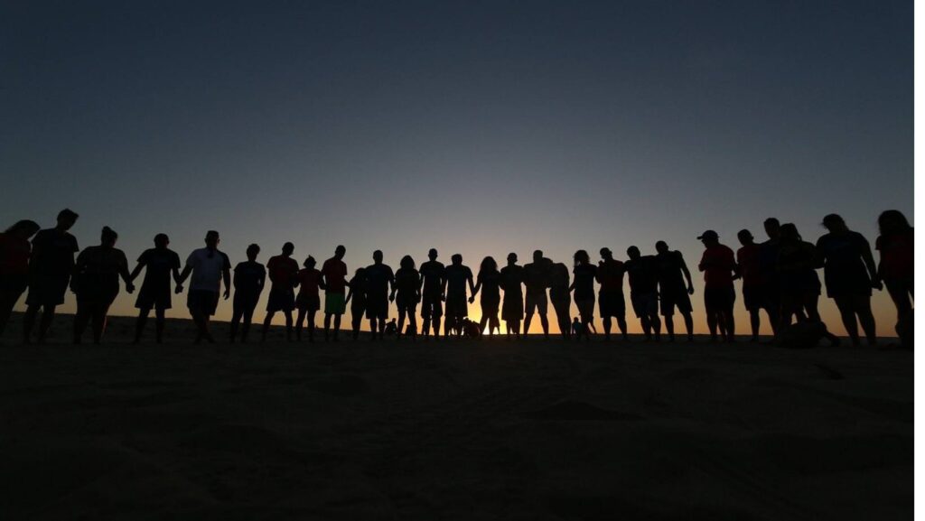 group of people silhouetted against a sunset