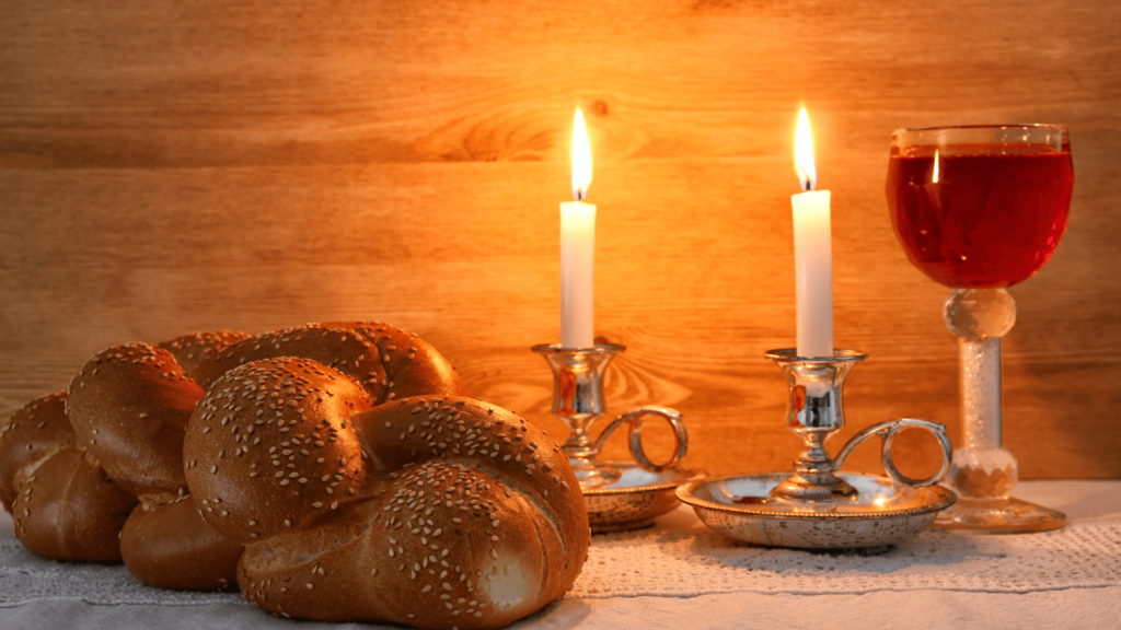 Shabbat candles, challah, and wine on a wood table