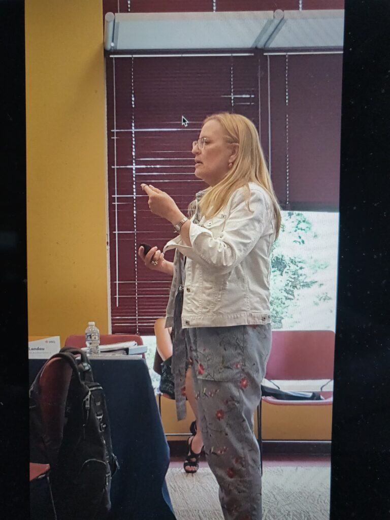 Sideview of Cyd Weissman speaking to a group.