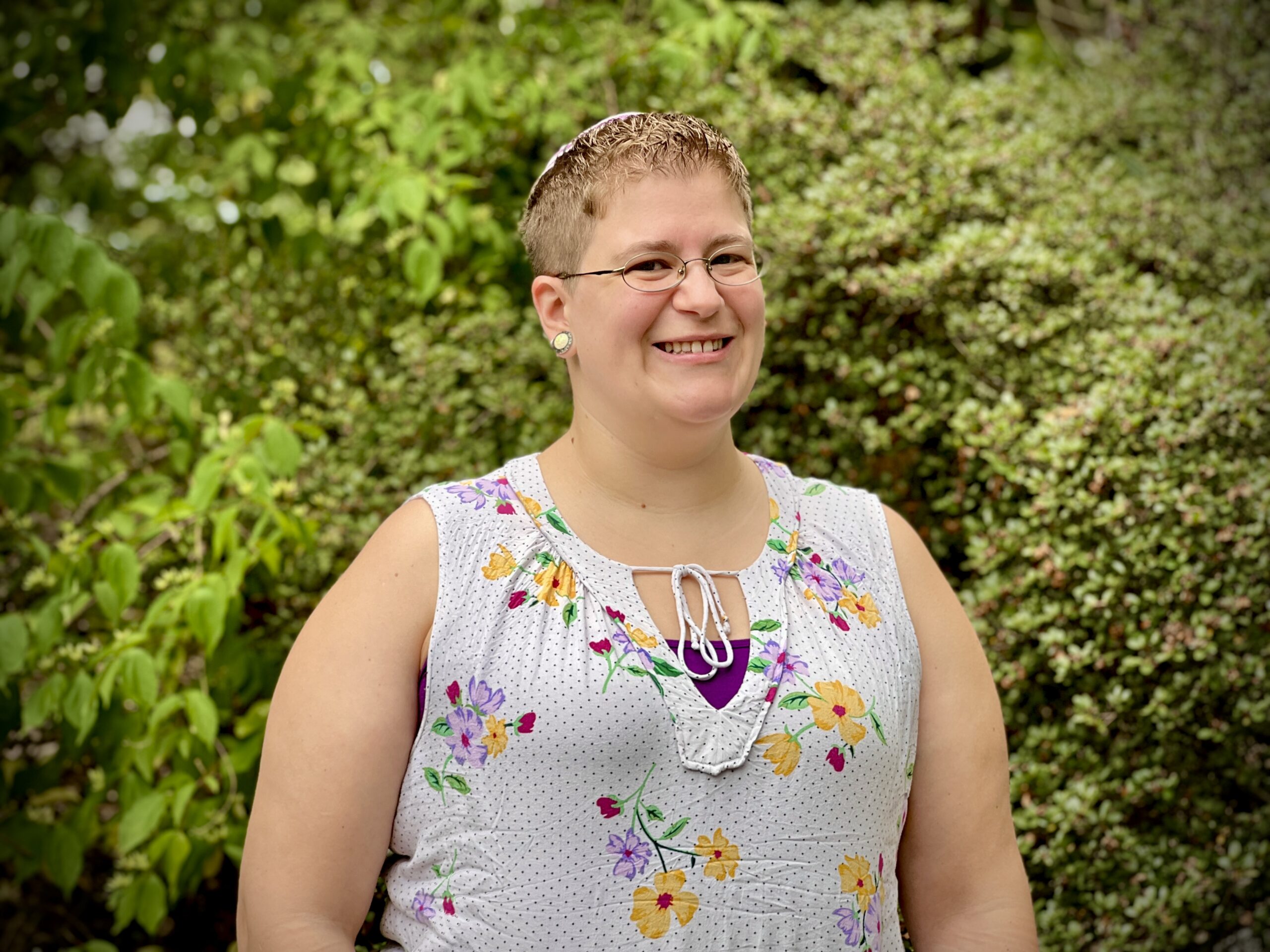 Rabbi Rayna Grossman poses in front of a tree outside the Reconstructionist Rabbinical College building.