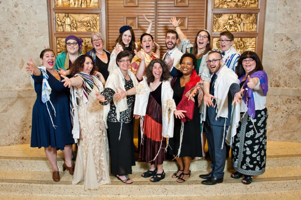 Members of RRCs class of 2017 pose on the bimah at graduation, many with arms outstretched. 