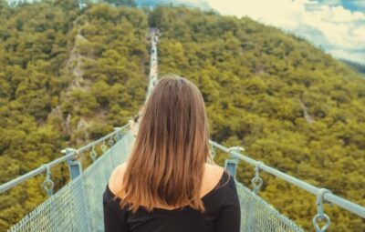 Woman walking across bridge over forest