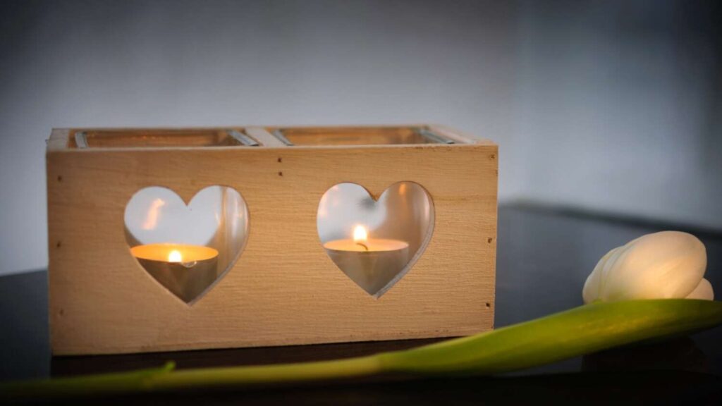 two candles in wooden box with heart-shaped windows