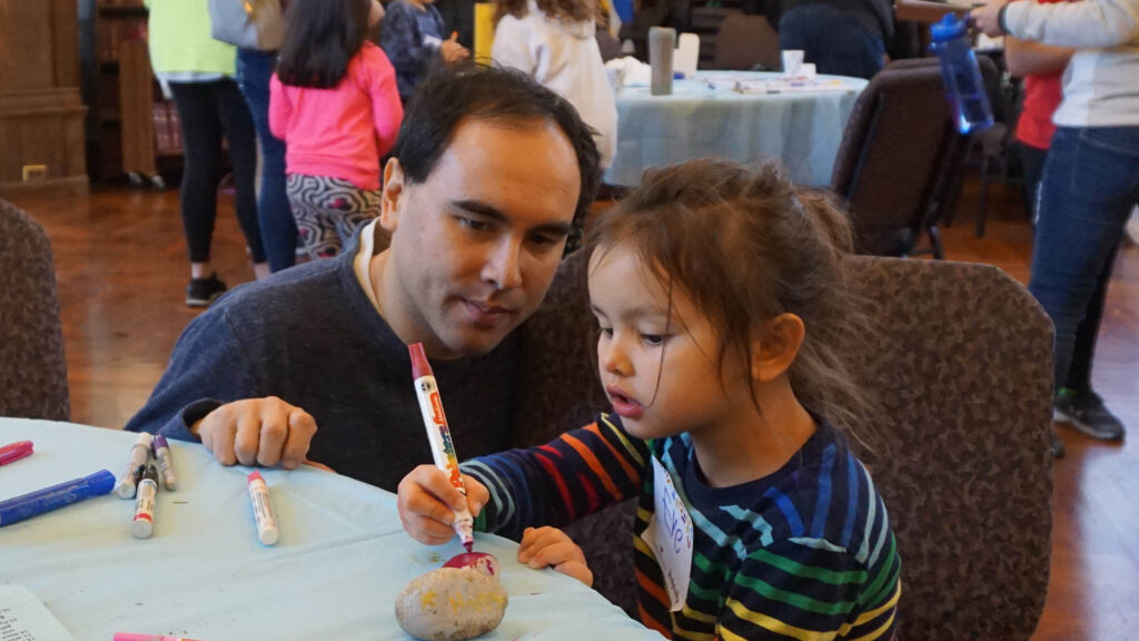 A little girl, presumably with her father, colors at a table in the synagogue.