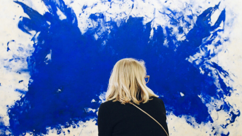 Woman facing an abstract blue paint splatter