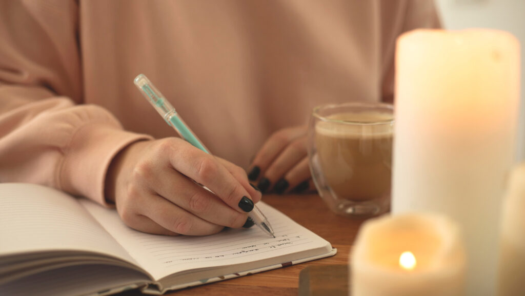 Person sitting with coffee writing in notebook