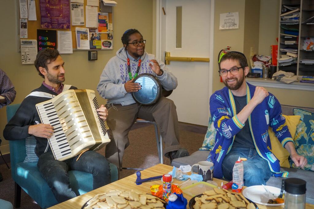 RRC students celebrate Hanukkah in the building. One plays an accordion while another plays a percussion instrument.