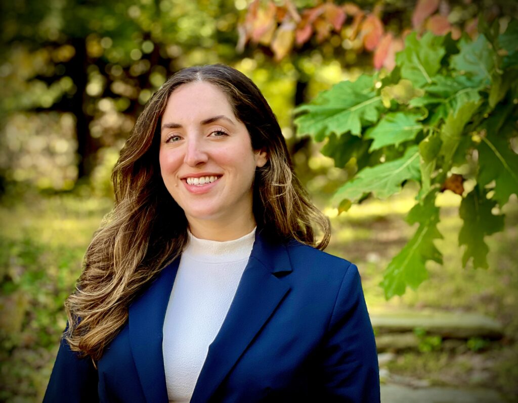 Rachel Robinson, wearing a blue blazer, poses in front of trees outside the Reconstructionist Rabbinical College.