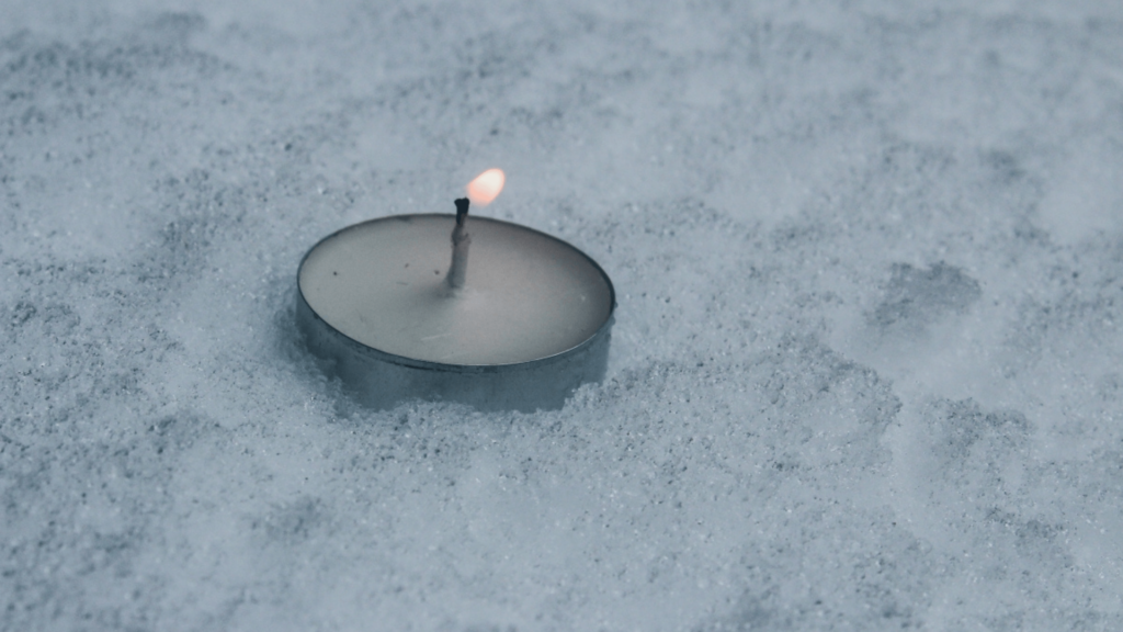 lit votive candle in the snow