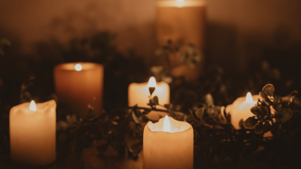 Lit candles in a dark space with plant branches