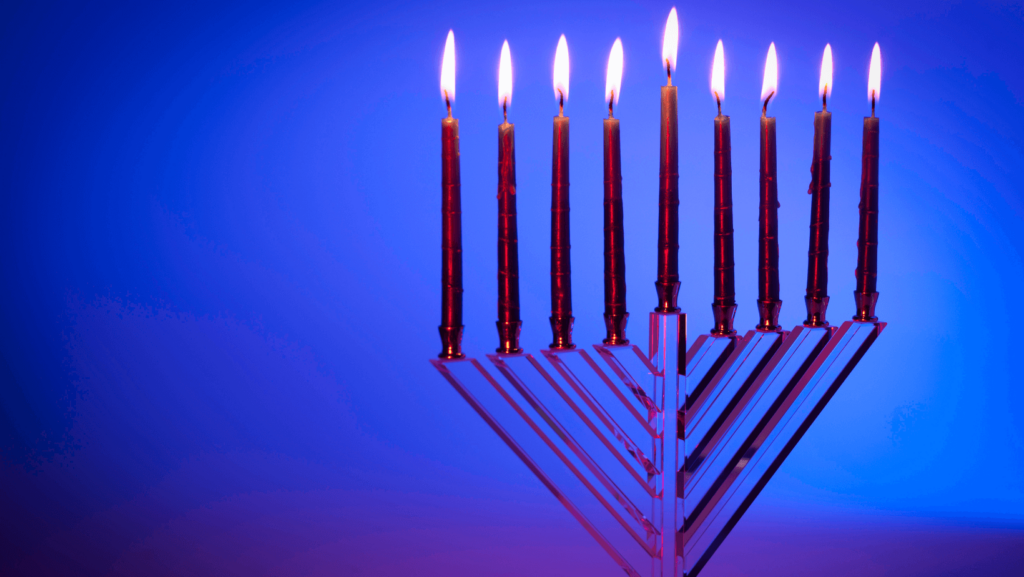 Glass menorah with red candles against a blue background