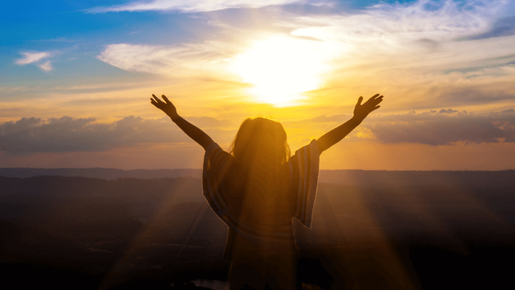 A person silhouetted against the sky with their arms outstretched