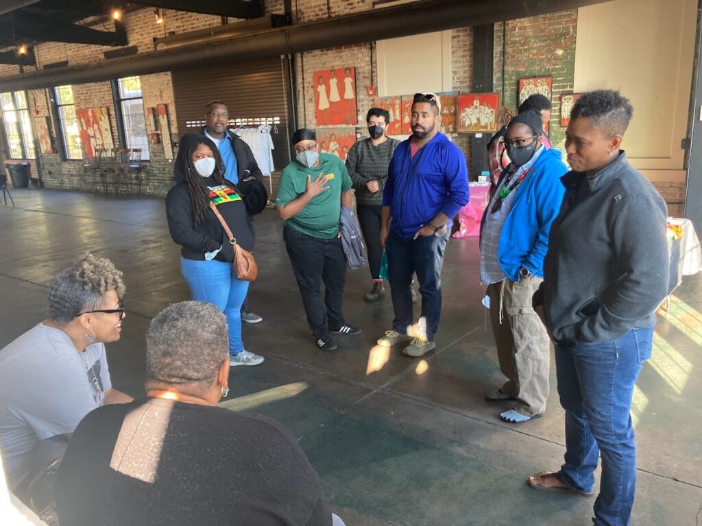 A group of Jews of African descent gather around in a loft-type building.