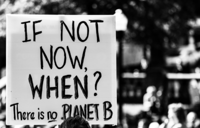 A protest sign reads, If not now, when? There is no planet B, in a crowd.