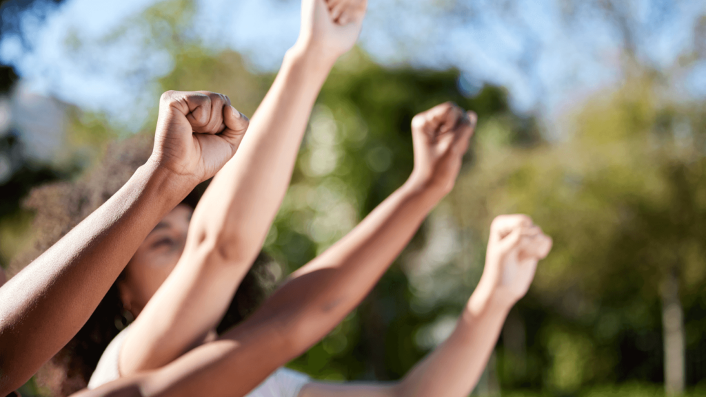 Close up on multiple people of different races raising their fists.