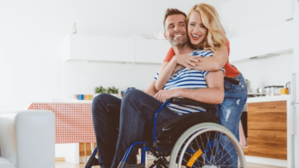 A blonde woman embracing a man in a wheelchair