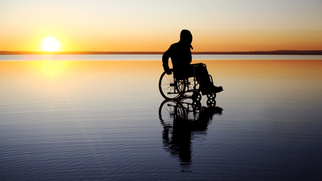 Silhouette of a person using a wheelchair outdoors at sunrise