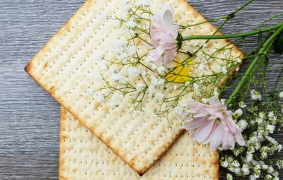 Two square crackers adorned with pink flowers and white babys breath on a wooden surface.