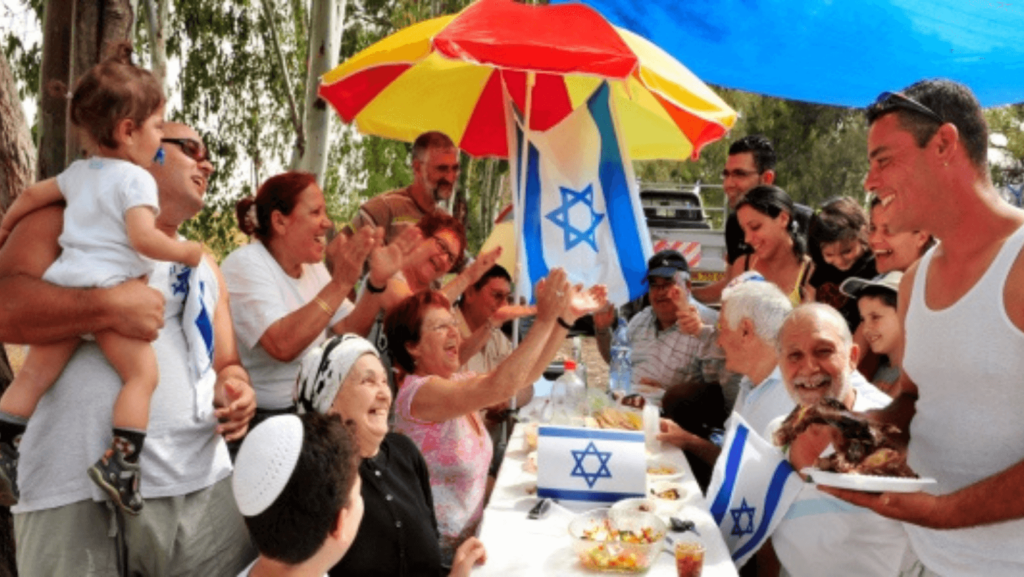 A family celebrating Israel's anniversary with Israeli flags at a picnic table