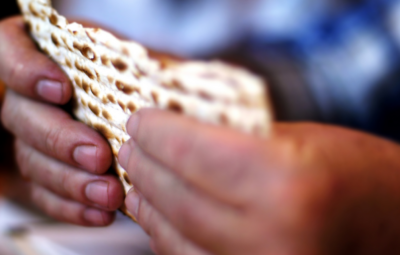 Hands holding a piece of matzah bread.