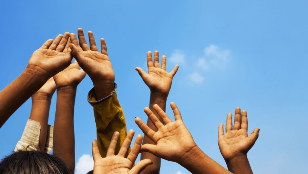 A group of people with their hands raised against a blue sky