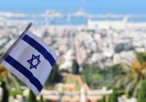 An Israeli flag in the foreground, Haifa and the Bahai Temple in the background.
