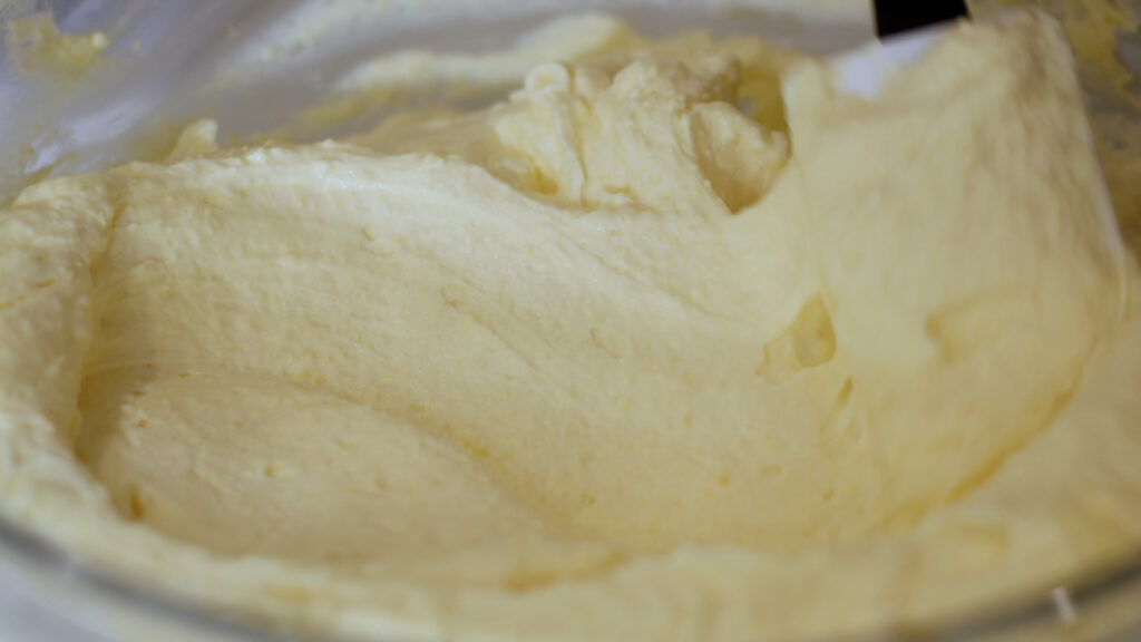 Close-up of creamy cake batter being mixed in a bowl.