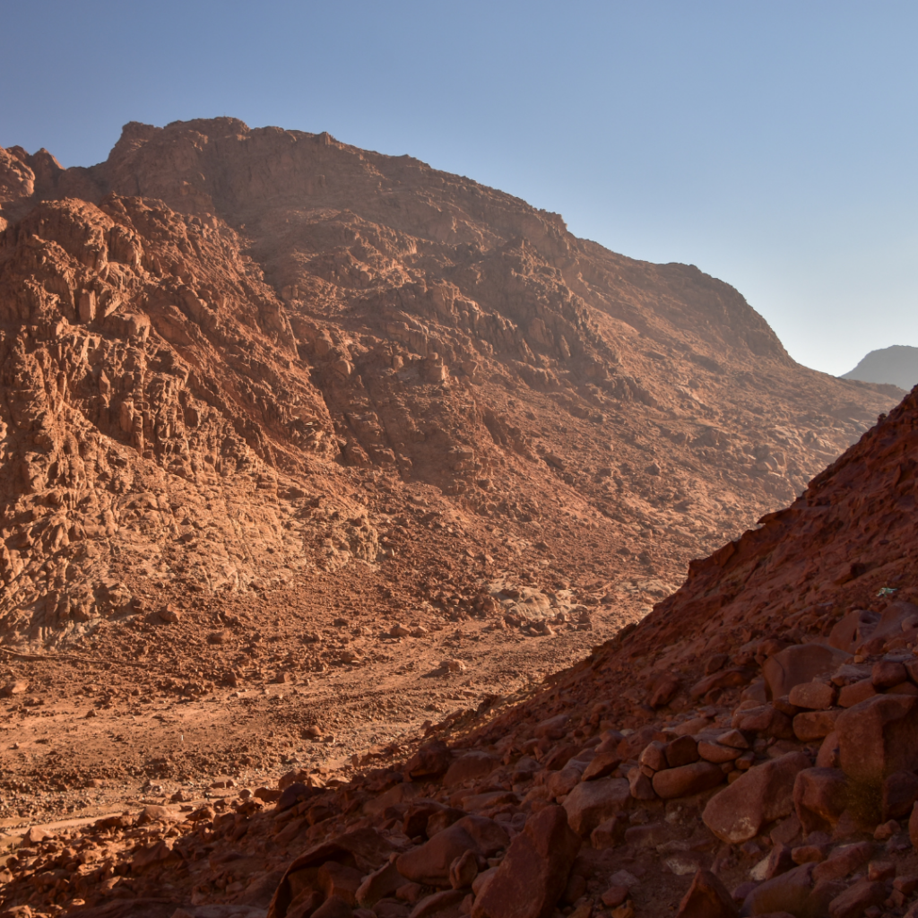 Rugged mountain landscape with rocky cliffs and clear blue sky in the background.