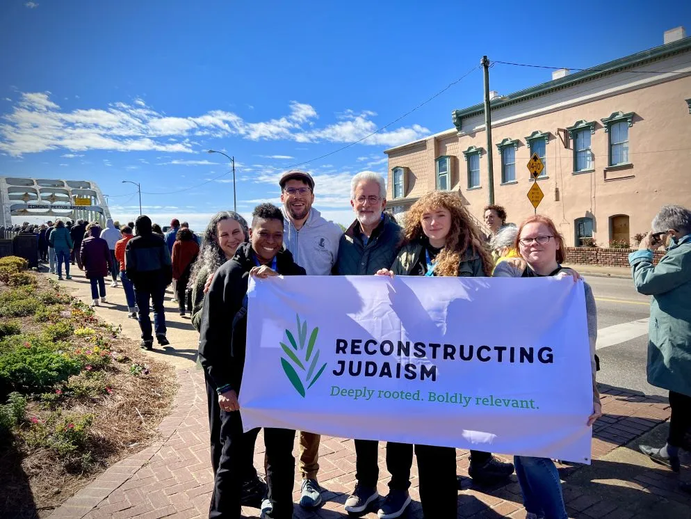 Staff membe display a Reconstructing Judaism banner standing near the Edmund Pettus Bridge in Selma, Ala.