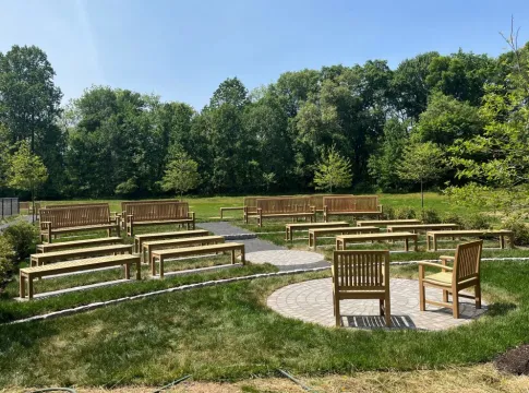 Benches in a cleared outdoor area, in front of trees.