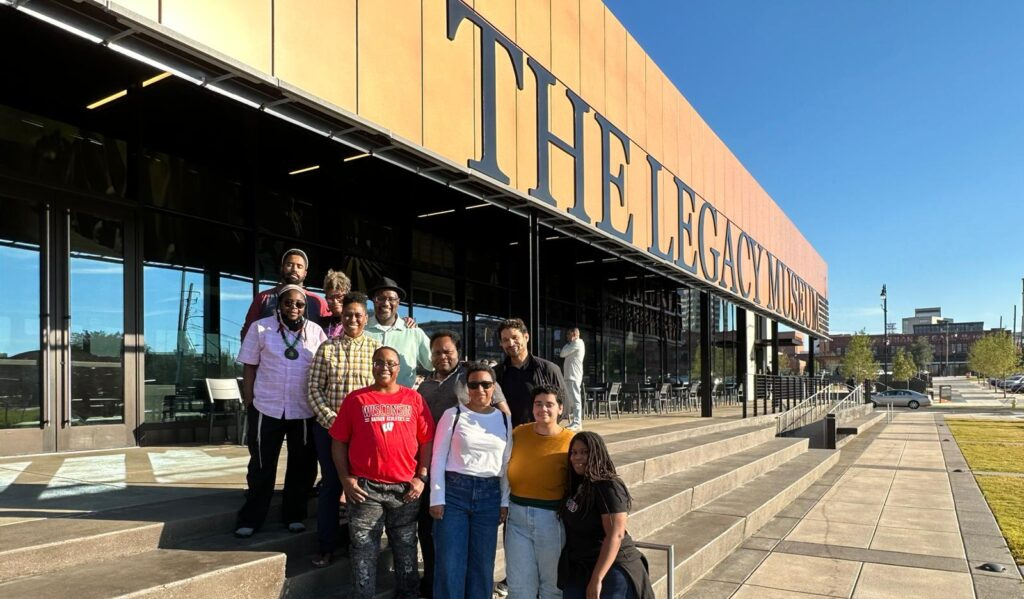 A group of people pose outside a building with The Legacy Museum sign.