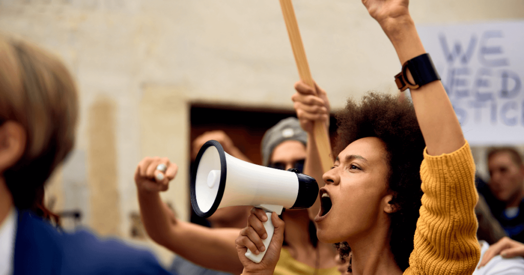 Black woman in a crowd yelling into a bullhorn