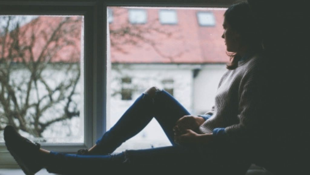 Woman sitting silhouetted against a window pane