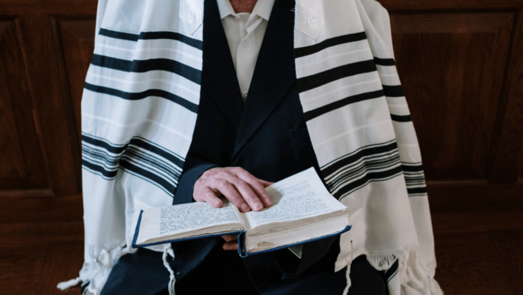 Close-up of a man wearing a prayer shawl and reading a prayer book
