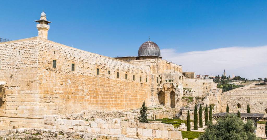 Ancient stone walls and Al-Aqsa Mosque with a blue sky background in Jerusalem.
