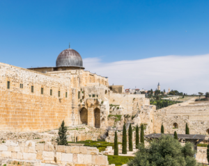 Ancient stone walls and Al-Aqsa Mosque with a blue sky background in Jerusalem.