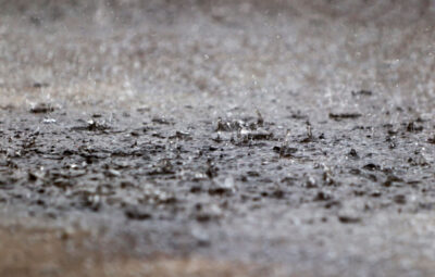 Raindrops splashing on a wet surface during a heavy rainfall, creating small ripples and splashes.