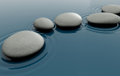 Smooth gray stones in calm blue water with gentle ripples.