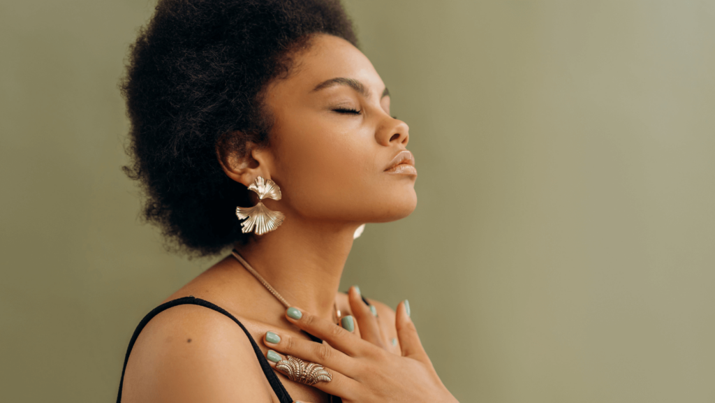 a Black woman in profile with her eyes closed and her hands touching her chest