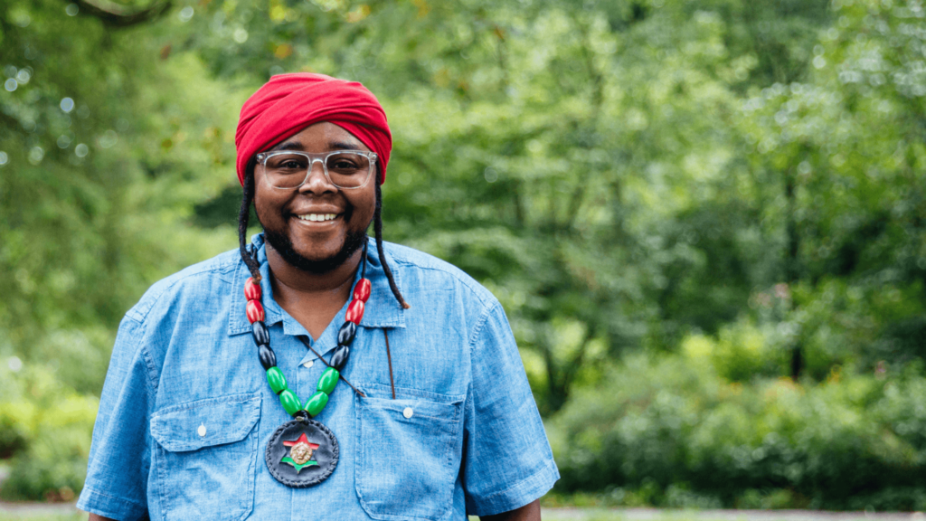 Koach Baruch Frazier wearing a red head scarf standing outside