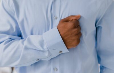 Person in a blue dress shirt holding their hand in a fist over their chest.
