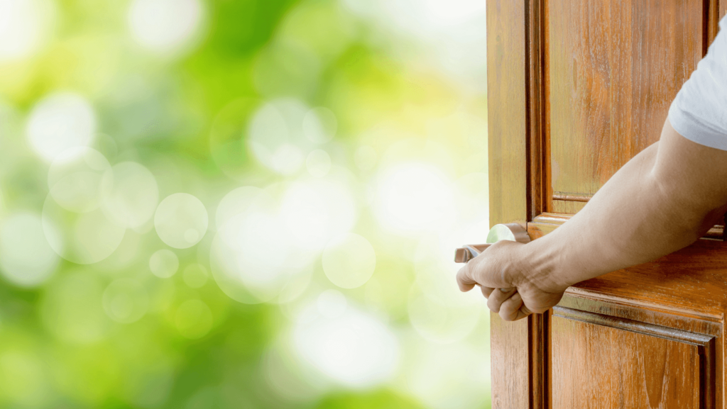 A person's hand opening up a wooden front door