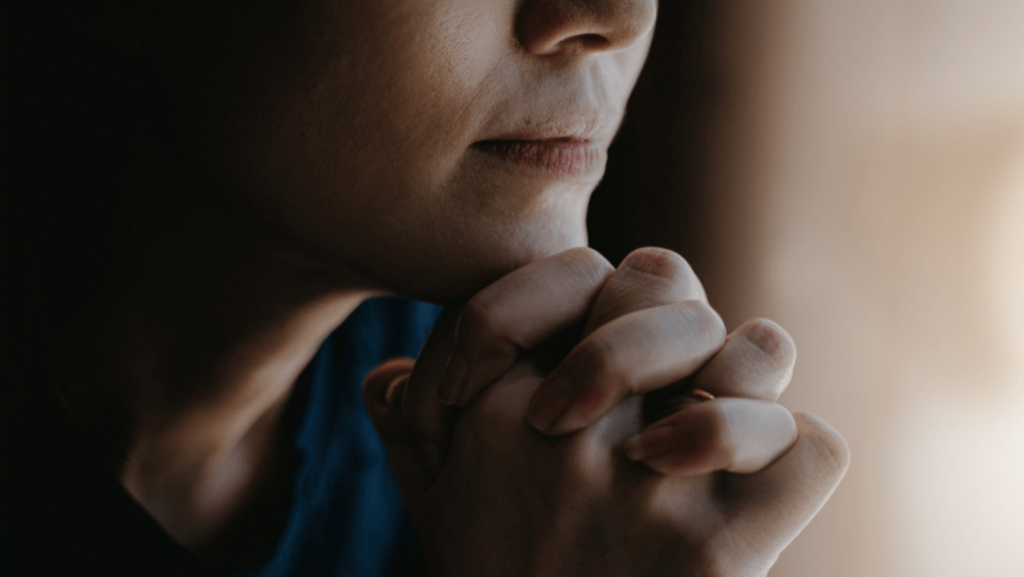 Close-up on a woman clasping her hands in prayer