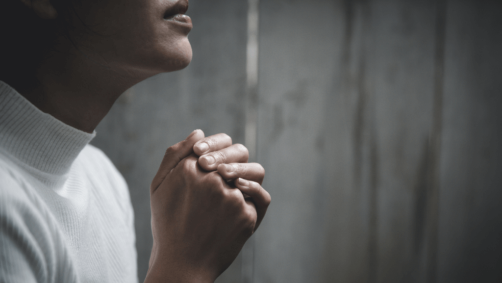 Close-up of someone praying with hands clasped in profile