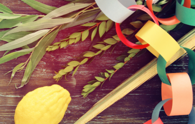 Colorful paper chain, etrog, and willow branches on a wooden surface.